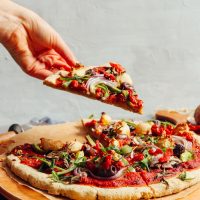 Picking up a slice of gluten-free and vegan pizza made using our Gluten-Free Pizza Crust recipe