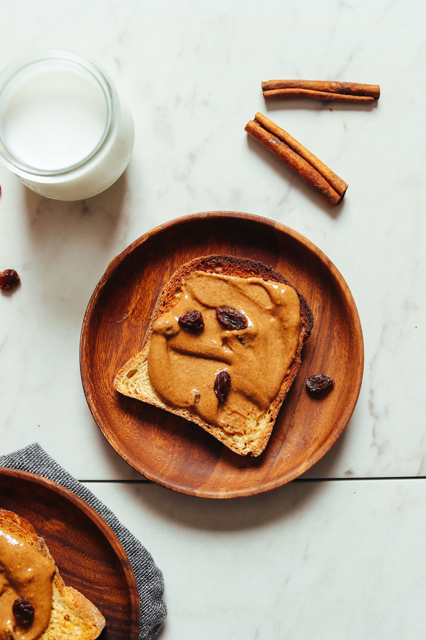 Slice of gluten-free toast smothered with delicious Cinnamon Raisin Peanut Butter for a healthy plant-based breakfast