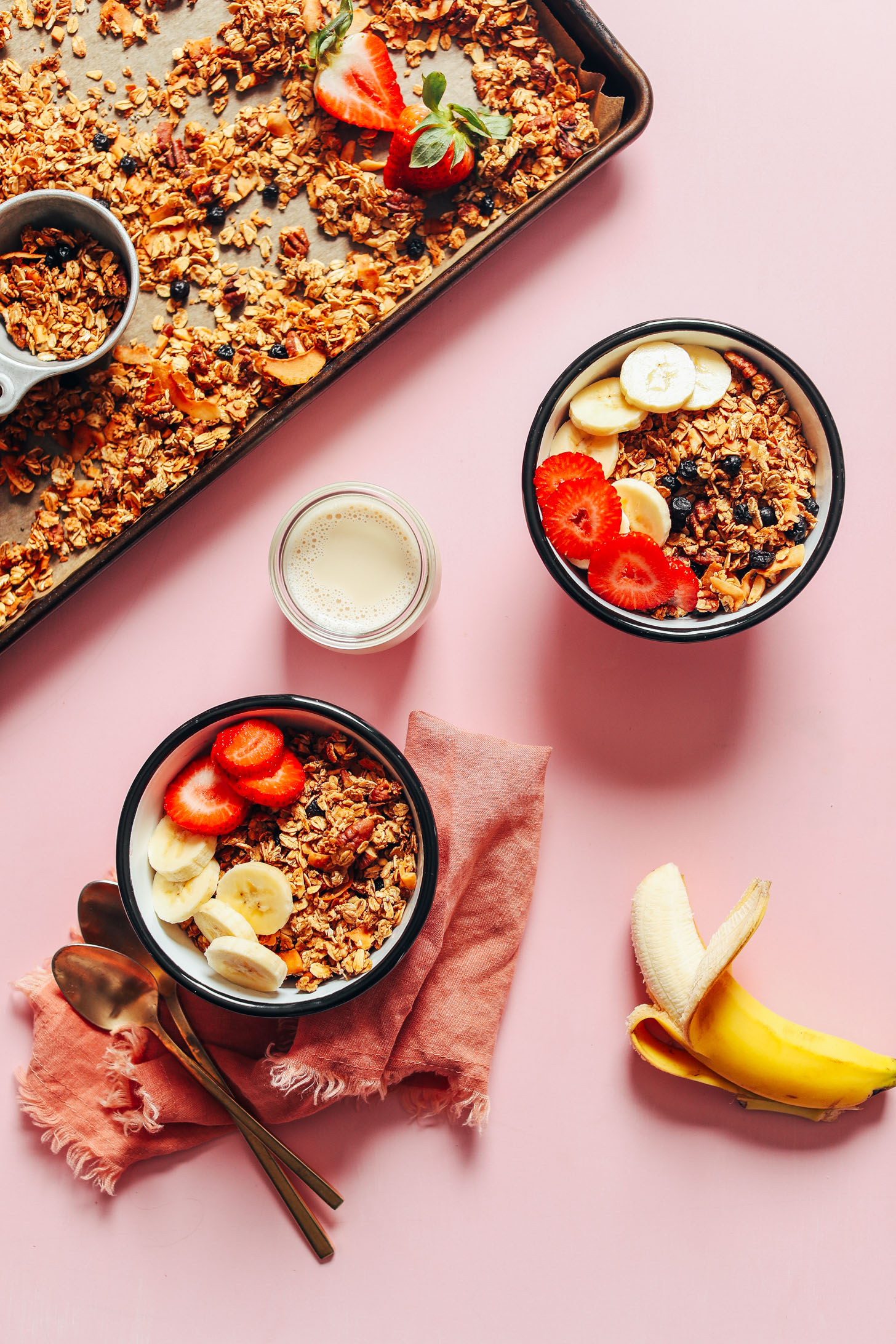 Two bowls of gluten-free homemade granola and dairy-free milk topped with fresh fruit