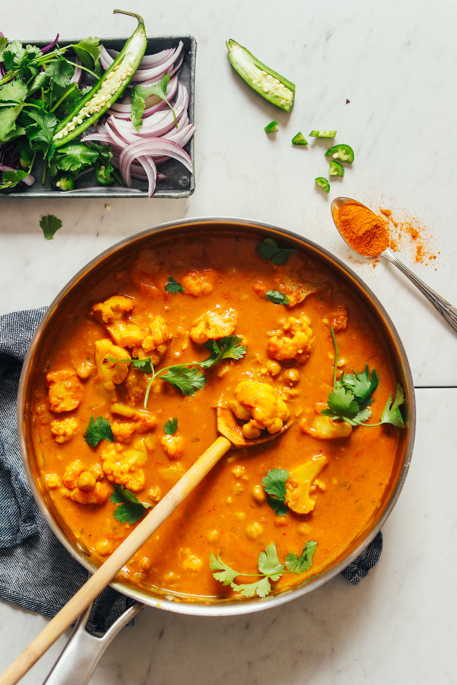 Stirring a pan of gluten-free vegan 1-Pot Yellow Chickpea Cauliflower Curry