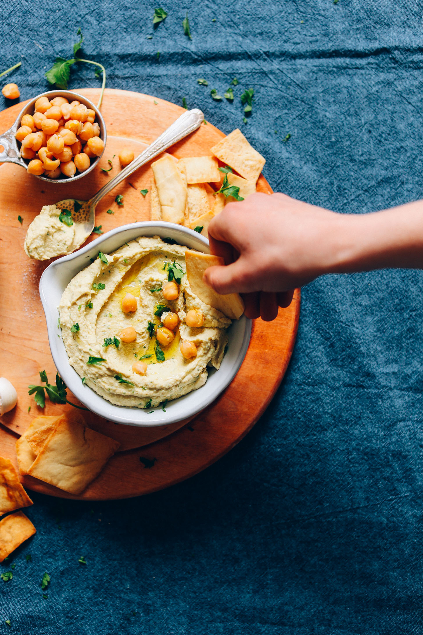 Dipping a cracker into a bowl of our homemade perfect hummus recipe