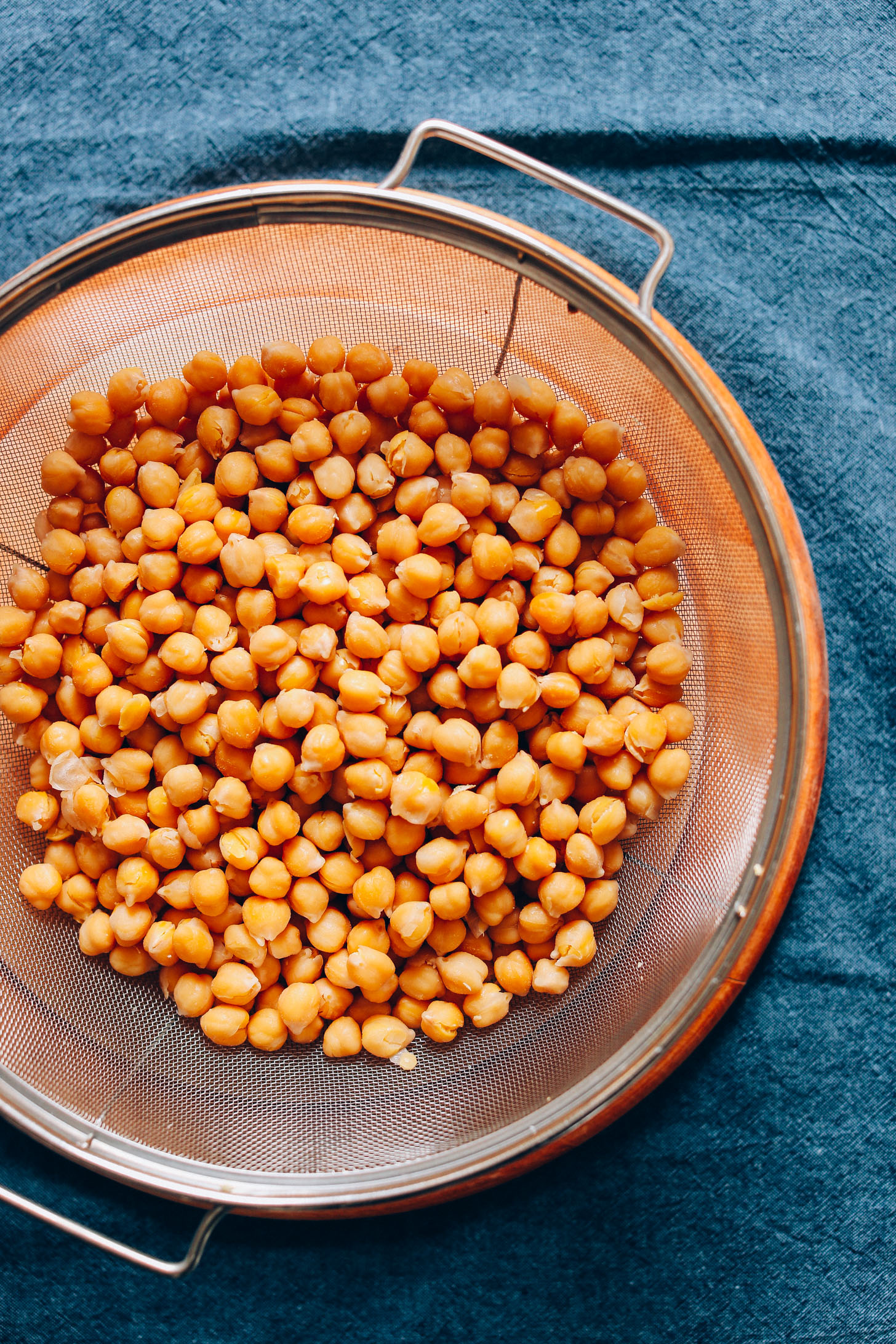 Draining chickpeas to make homemade hummus for a protein-packed vegan snack