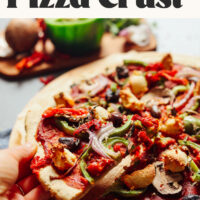 Picking up a slice of pizza from a cutting board made with our easy gluten-free pizza crust