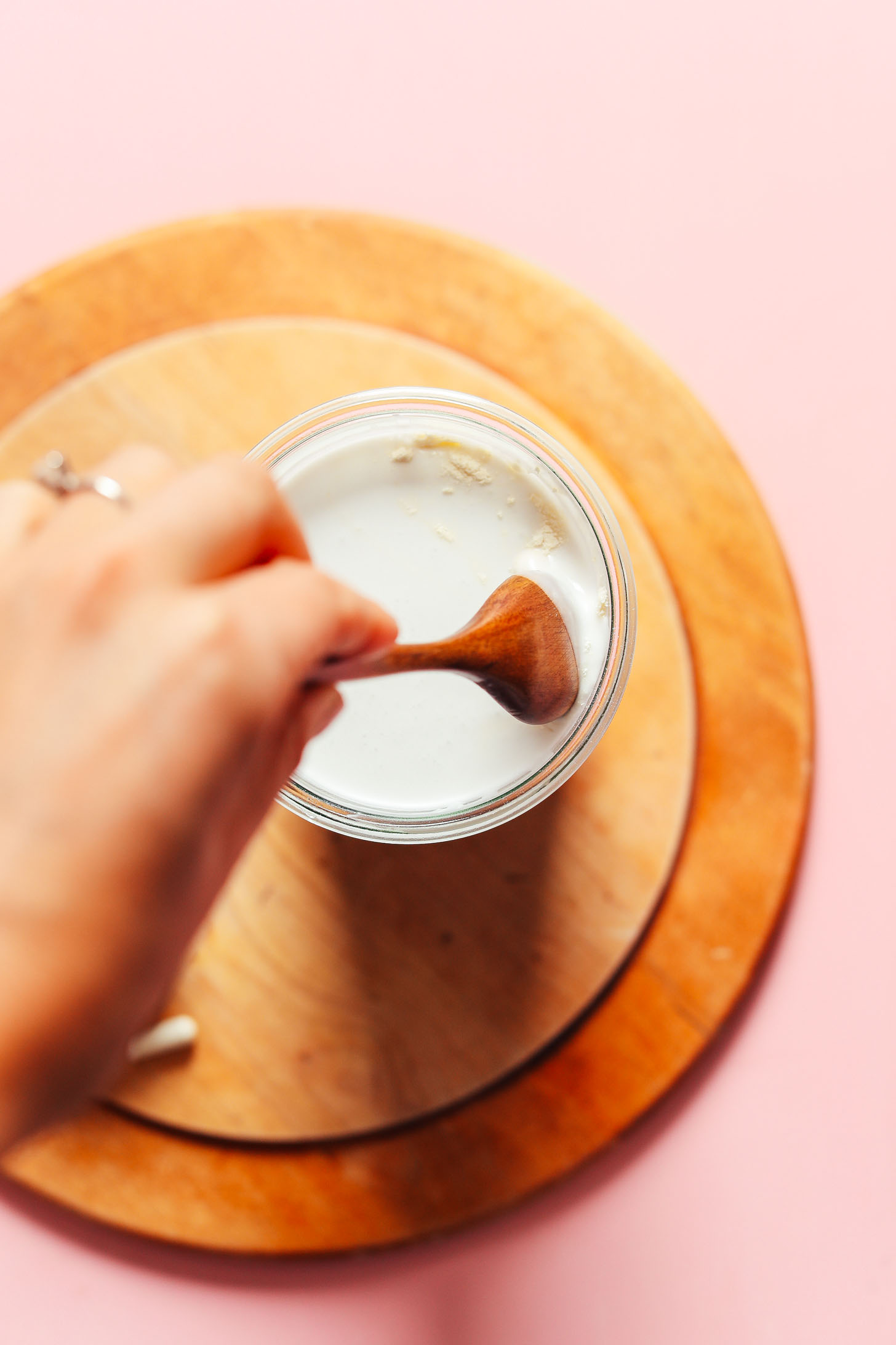 Using a wooden spoon to stir homemade gluten-free plant-based Mango Coconut Yogurt