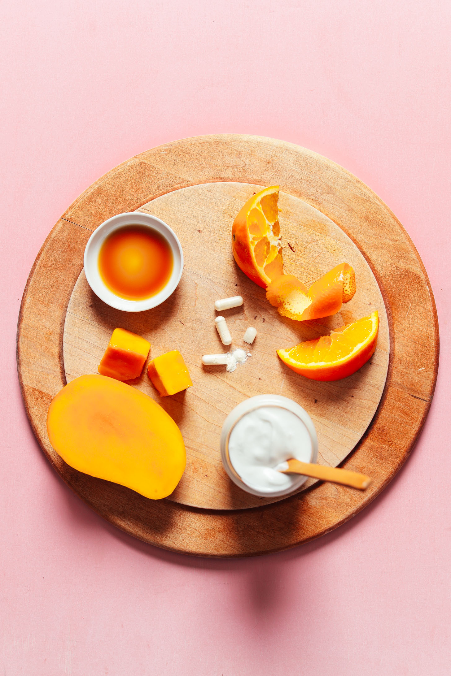 Wood cutting board with mango, coconut milk, orange, probiotics, and maple syrup for making homemade yogurt