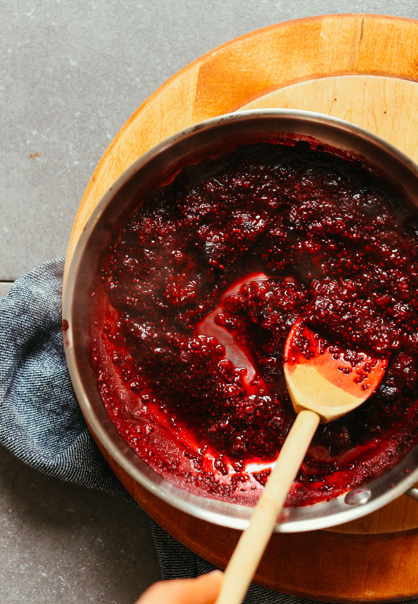Using a wooden spoon to stir berry compote in a saucepan for the best gluten-free steel cut oats