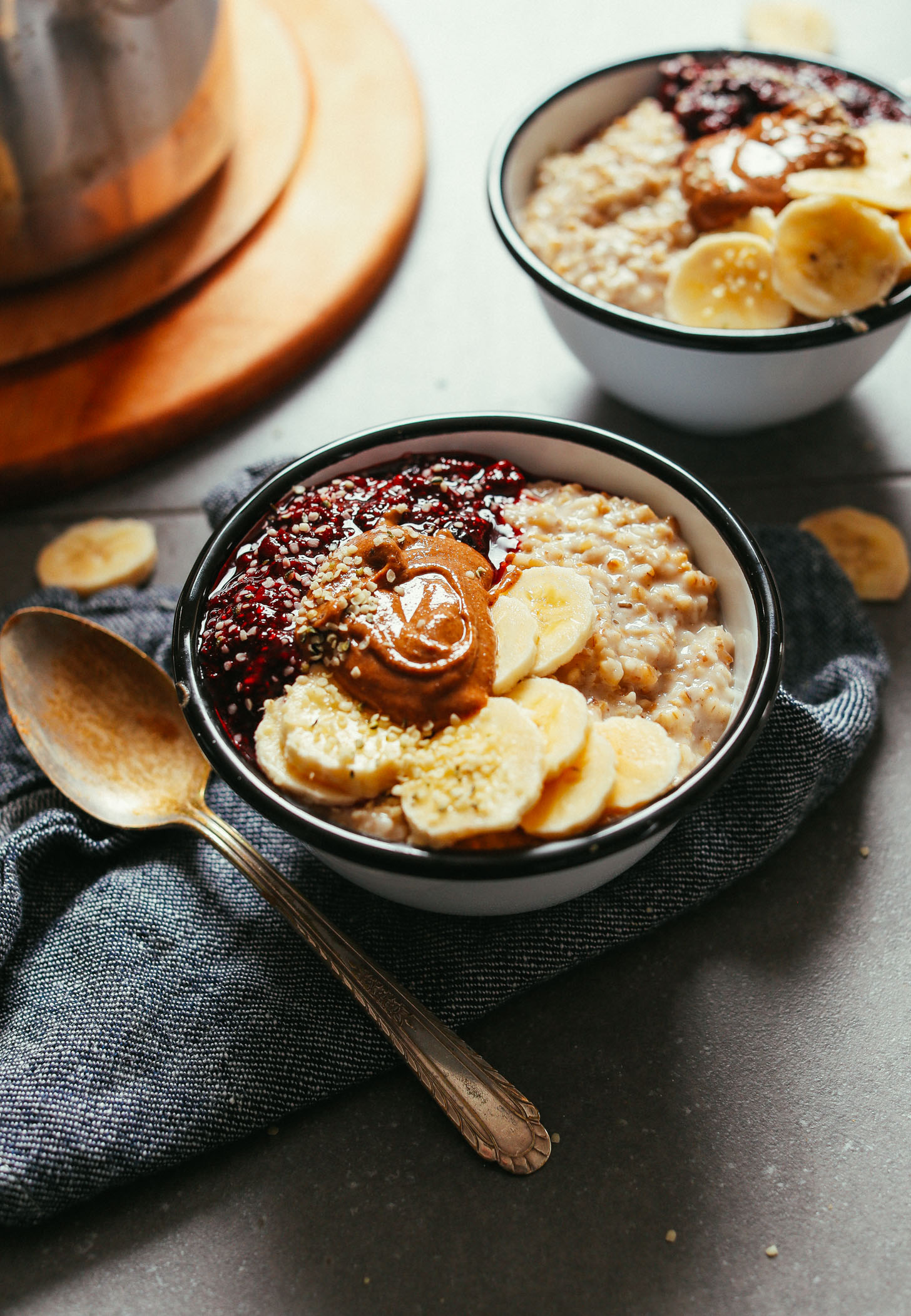 Close up shot showing two bowls of perfectly cooked steel cut oats topped with fruit and nut butter