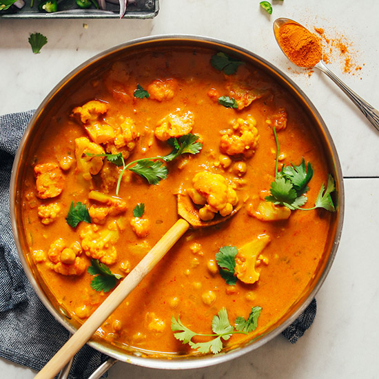 Wooden spoon in a pot of Vegan Yellow Chickpea Curry