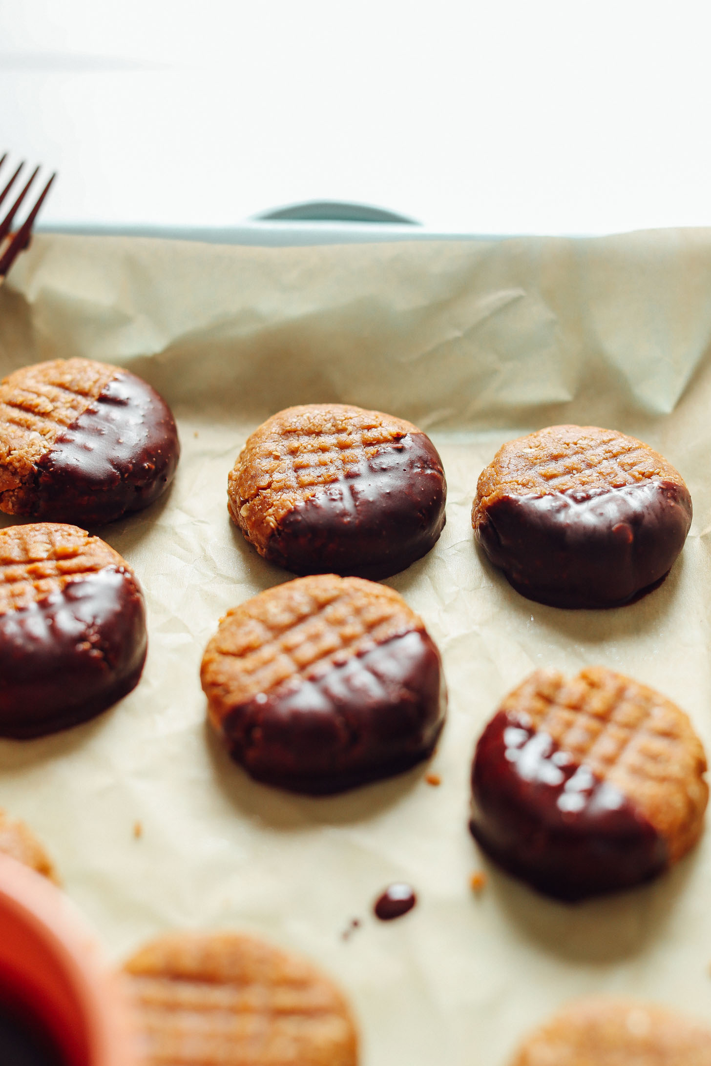 Parchment-lined baking sheet with chocolate-dipped gluten-free peanut butter cookies