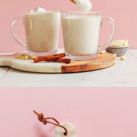 Mugs of Vegan White Hot Chocolate topped with coconut whipped cream and cinnamon
