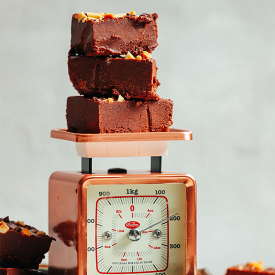 Slices of our 4-Ingredient Freezer Fudge recipe stacked on a vintage scale