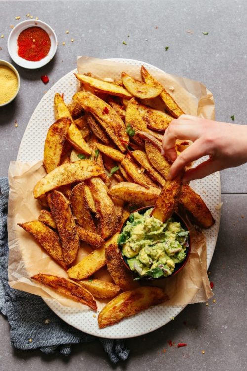 Dipping an oil-free potato fry into guac for a healthy plant-based snack