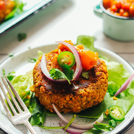 Plate with a Curried Quinoa Burger topped with sliced onion, jalapeno, and mango chutney