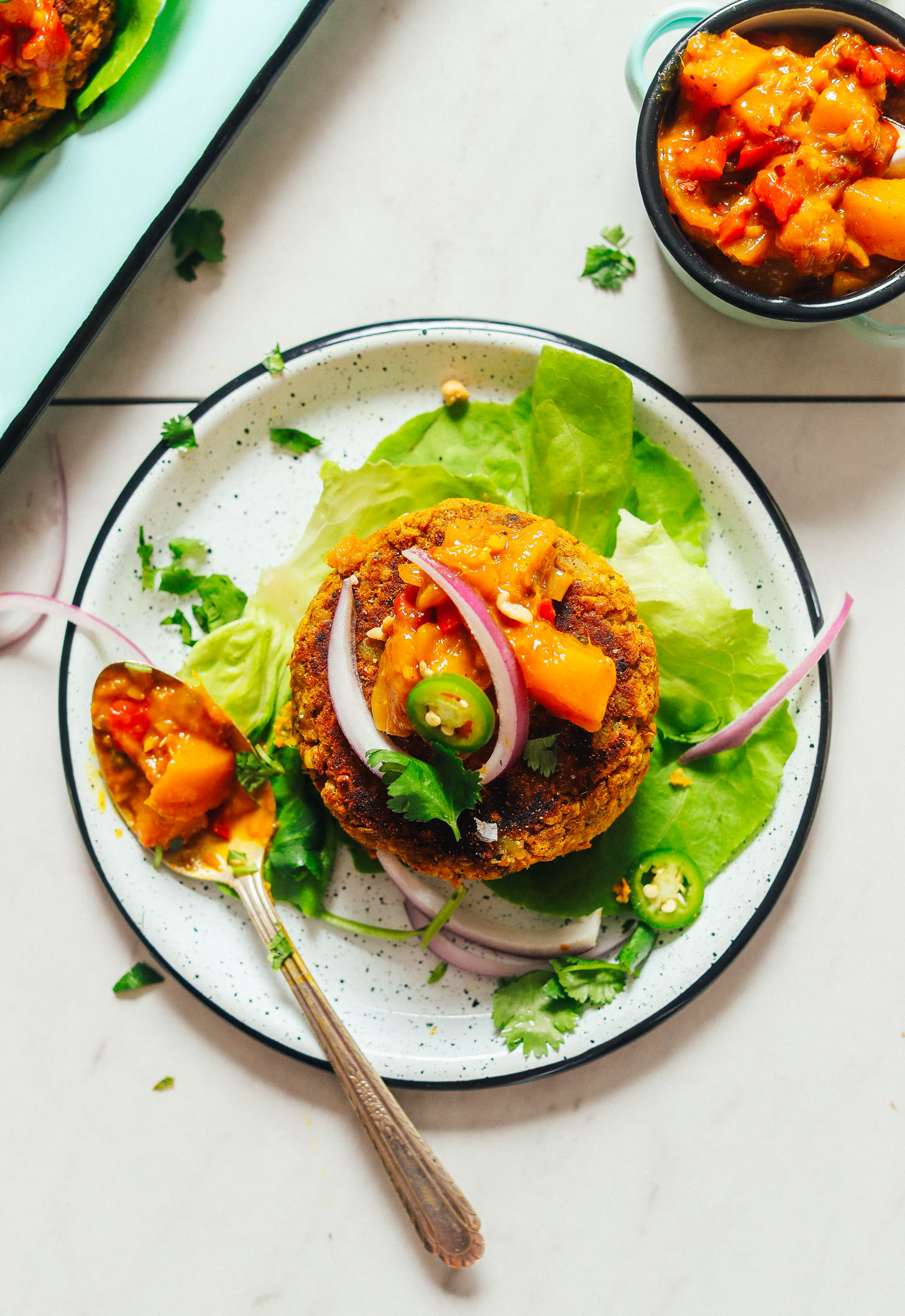 Butter lettuce leaf topped with a Curried Chickpea Burger, mango chutney, red onion, and jalapeno