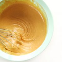 Whisking together homemade peanut sauce in a mixing bowl