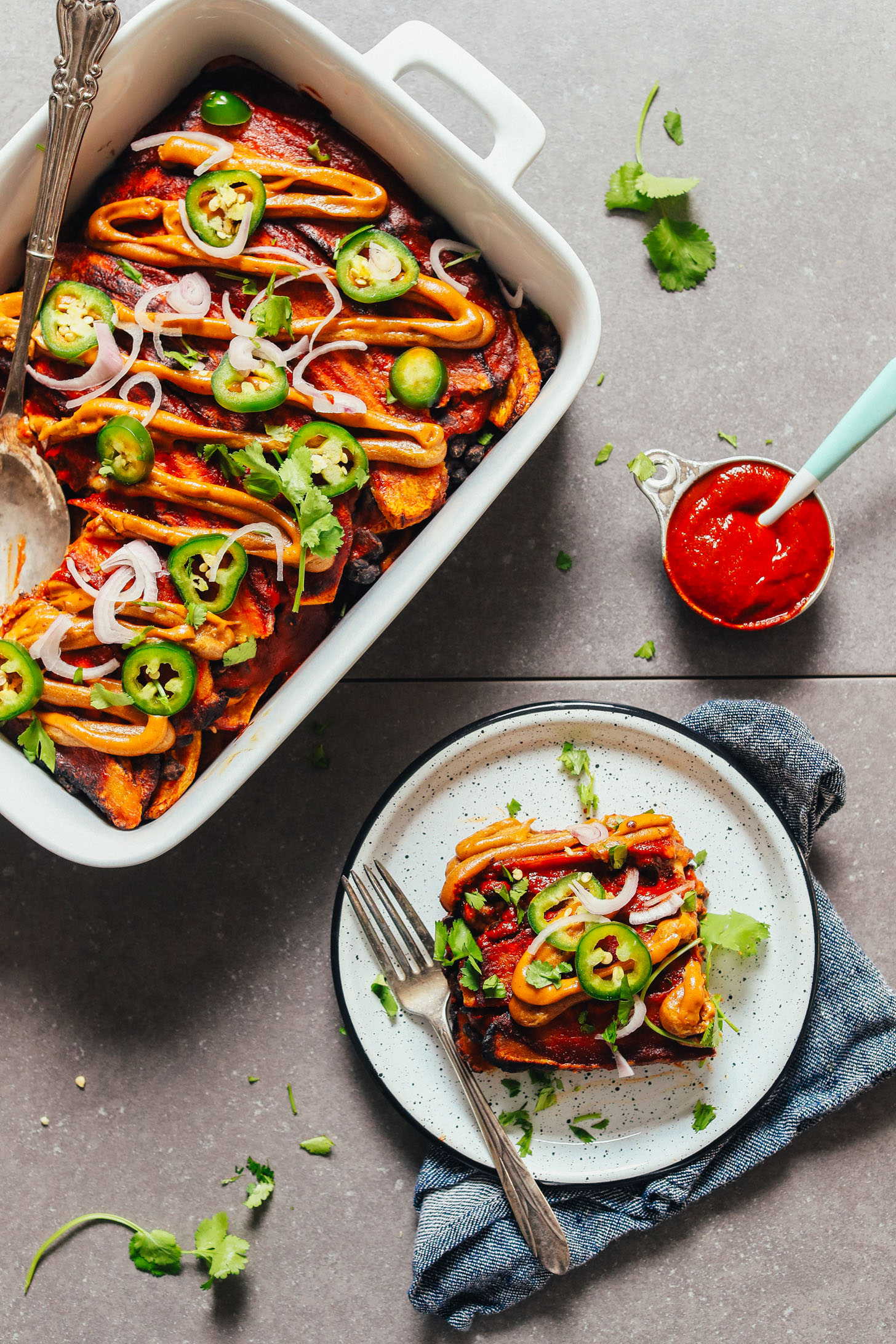 Plantain Black Bean Enchilada Bake topped with Vegan Queso, sliced jalapeños, and shallot
