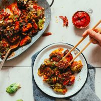 Using chopsticks to grab a bite of our Gochujang Stir-Fried Brussels Sprouts recipe