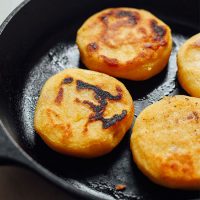Homemade arepas cooking in a cast-iron skillet