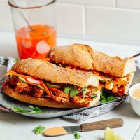 Tray displaying two gluten-free vegan Cauliflower Banh Mi sandwiches with a jar of pickled veggies behind it