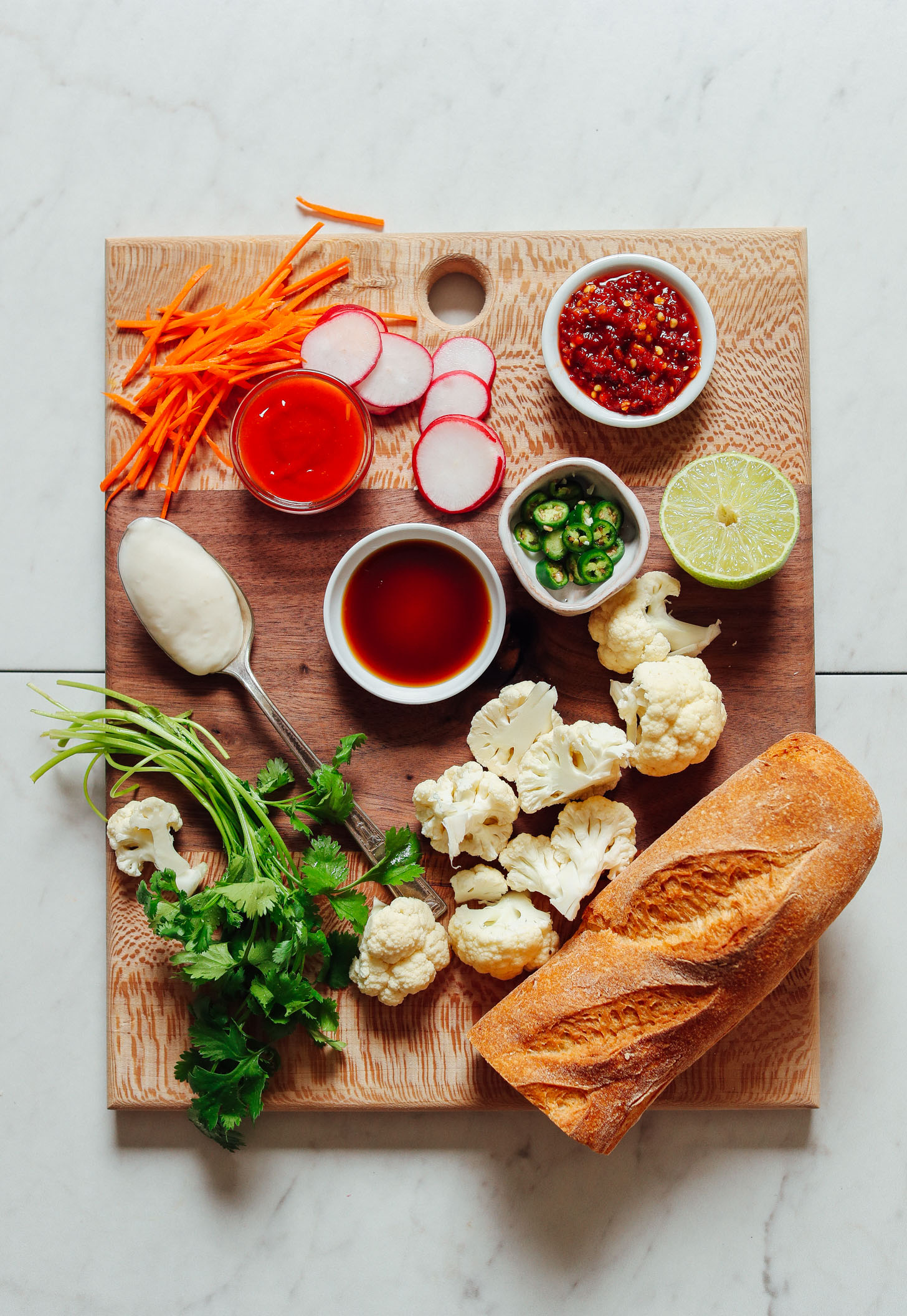Wood cutting board filled with ingredients for making our Cauliflower Banh Mi recipe