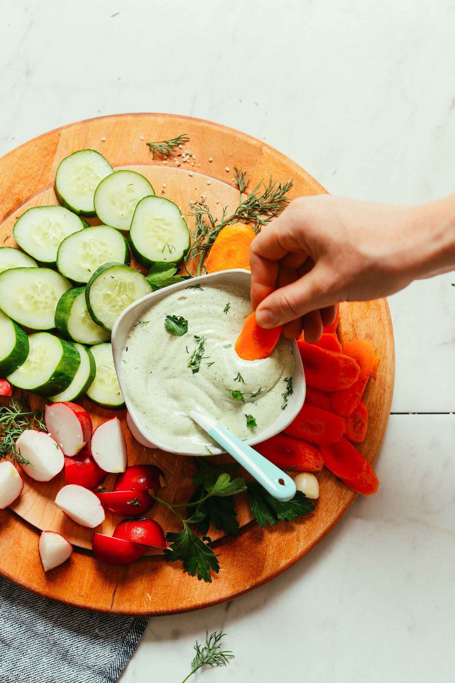 Dipping a carrot slice into a bowl of our Creamy Vegan Ranch dressing recipe