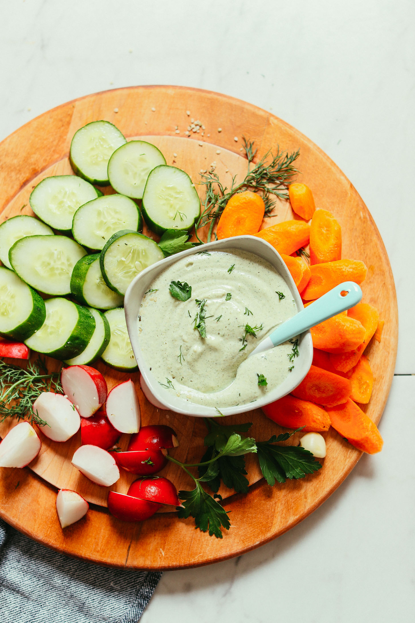 Wood cutting board filled with veggies and a bowl of our Creamy Vegan Ranch Dressing