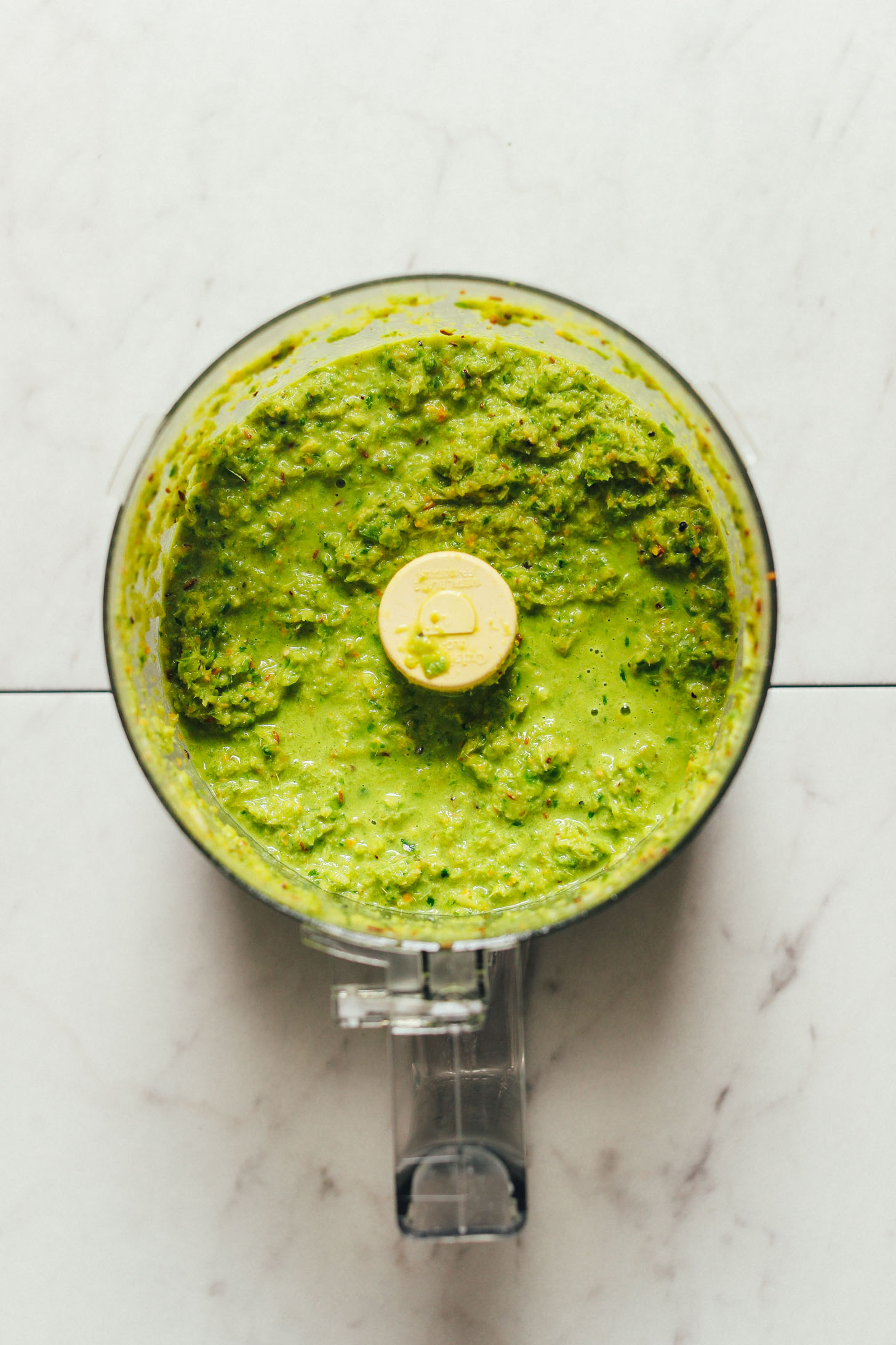 Overhead image of food processor with blended green curry paste