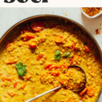 Ladle resting in a pan of our 1-pot golden curry lentil soup that's ready in 30 minutes