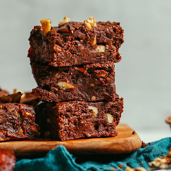 Stack of three Easy Vegan Brownies on a wood cutting board