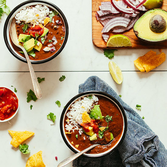 Bowls of our delicious 1-Pot Black Bean Soup topped with avocado, tortilla chips, and avocado