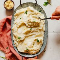 Using a serving spoon to scoop Garlic Mashed Cauliflower from a tray