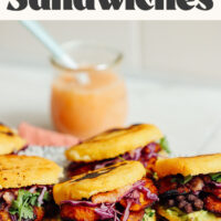 Black bean and plantain arepa sandwiches with hot sauce in the background