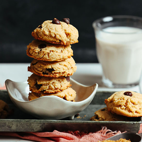Tray and bowl with our Vegan GF Chocolate Chip Cookies alongside a glass of dairy-free milk