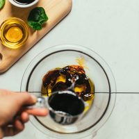 Pouring balsamic vinegar into a bowl for homemade Balsamic Vinaigrette Dressing