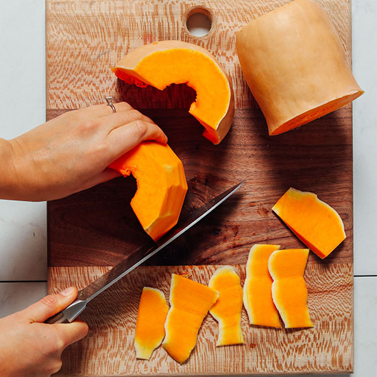 Using a knife to cut the peel off of butternut squash