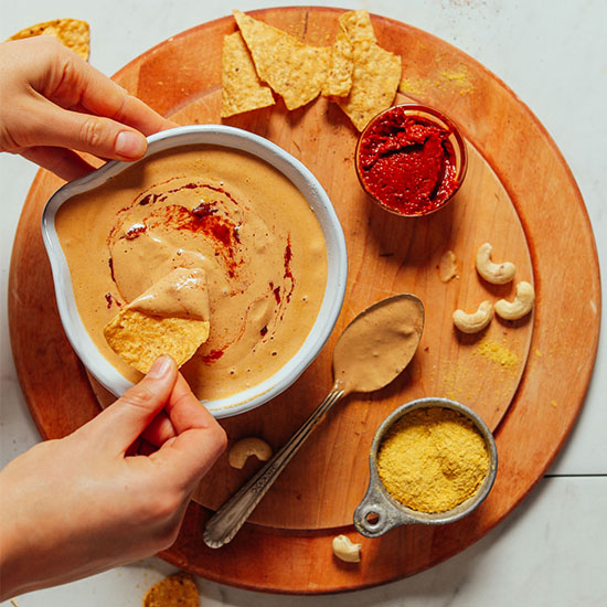 Dipping a chip into a bowl of Vegan Cashew Queso