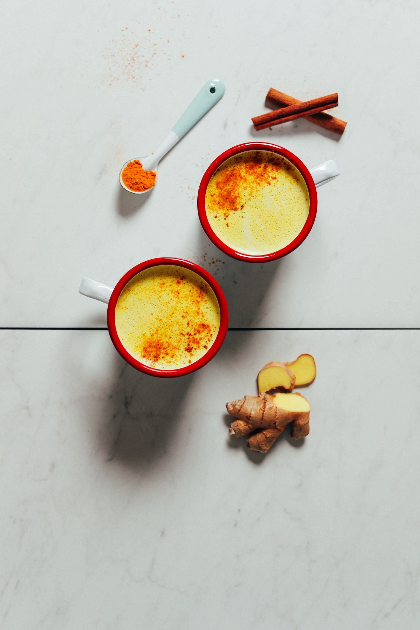 Two mugs of creamy Golden Milk surrounded by anti-inflammatory spices