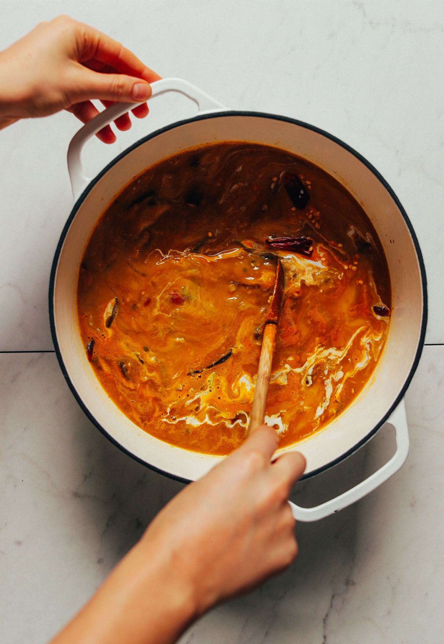 Using a wooden spoon to stir a batch of our homemade Vegan Tom Yum Soup recipe