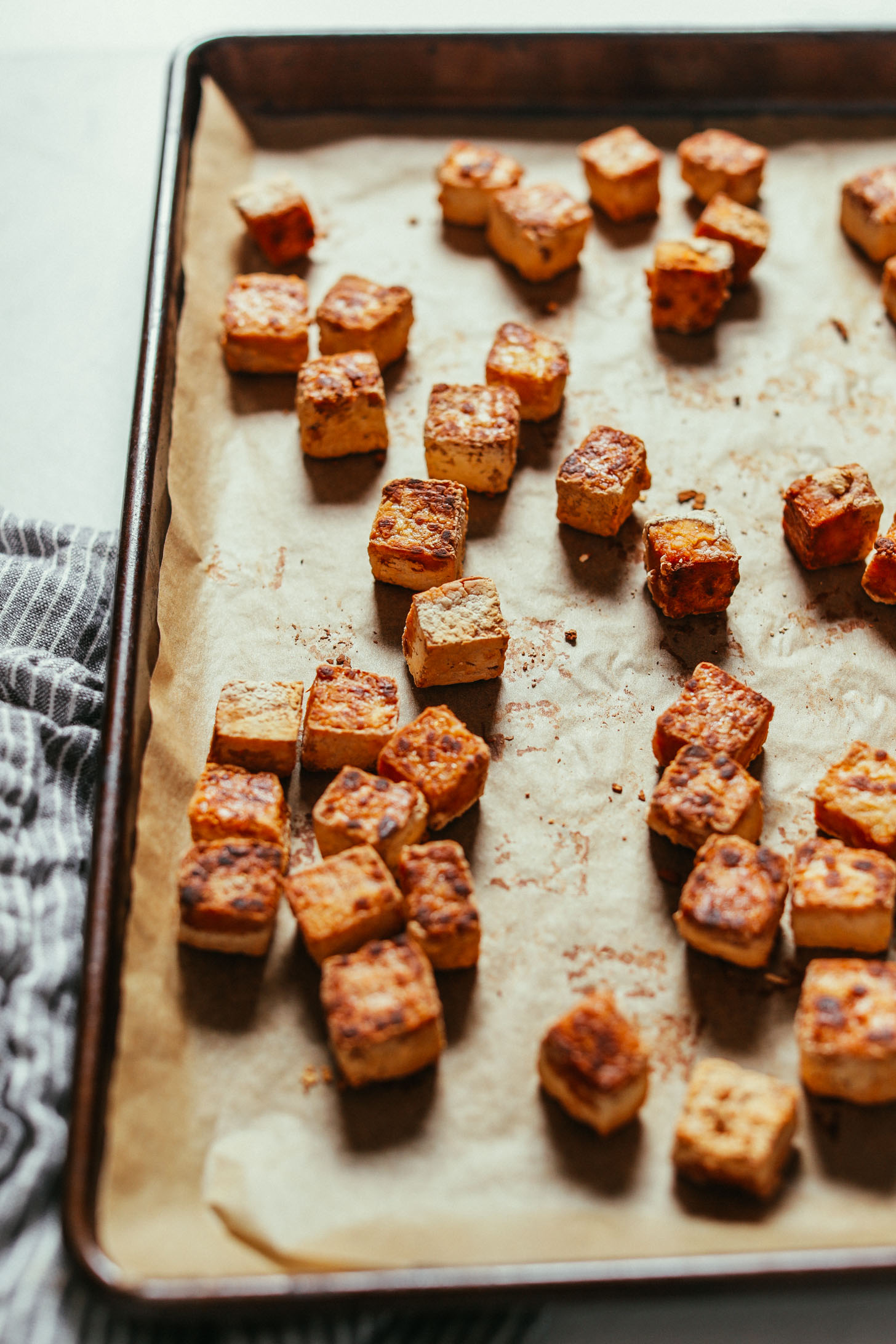 Parchment-lined baking sheet filled with Crispy Tofu fresh from the oven