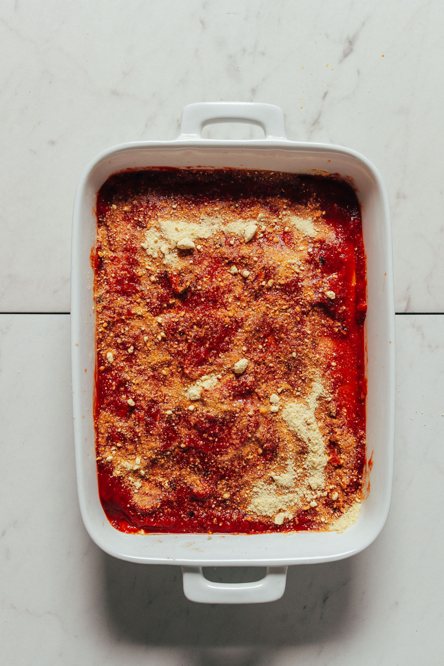Ceramic baking pan filled with a batch of our Easy Vegan Lasagna topped with Vegan Parmesan