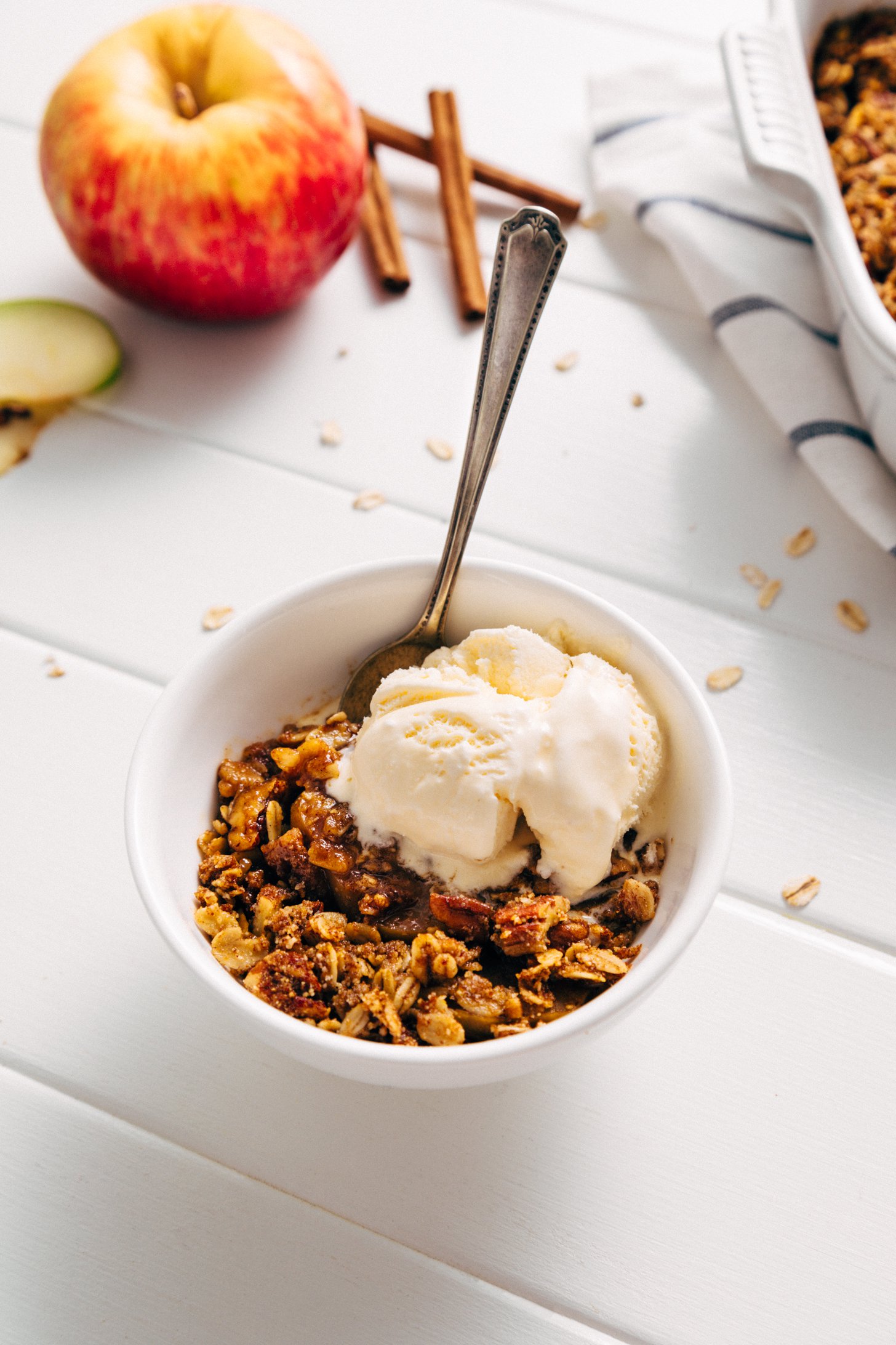 Spoon in a bowl of healthy Apple Crisp with a scoop of vanilla ice cream
