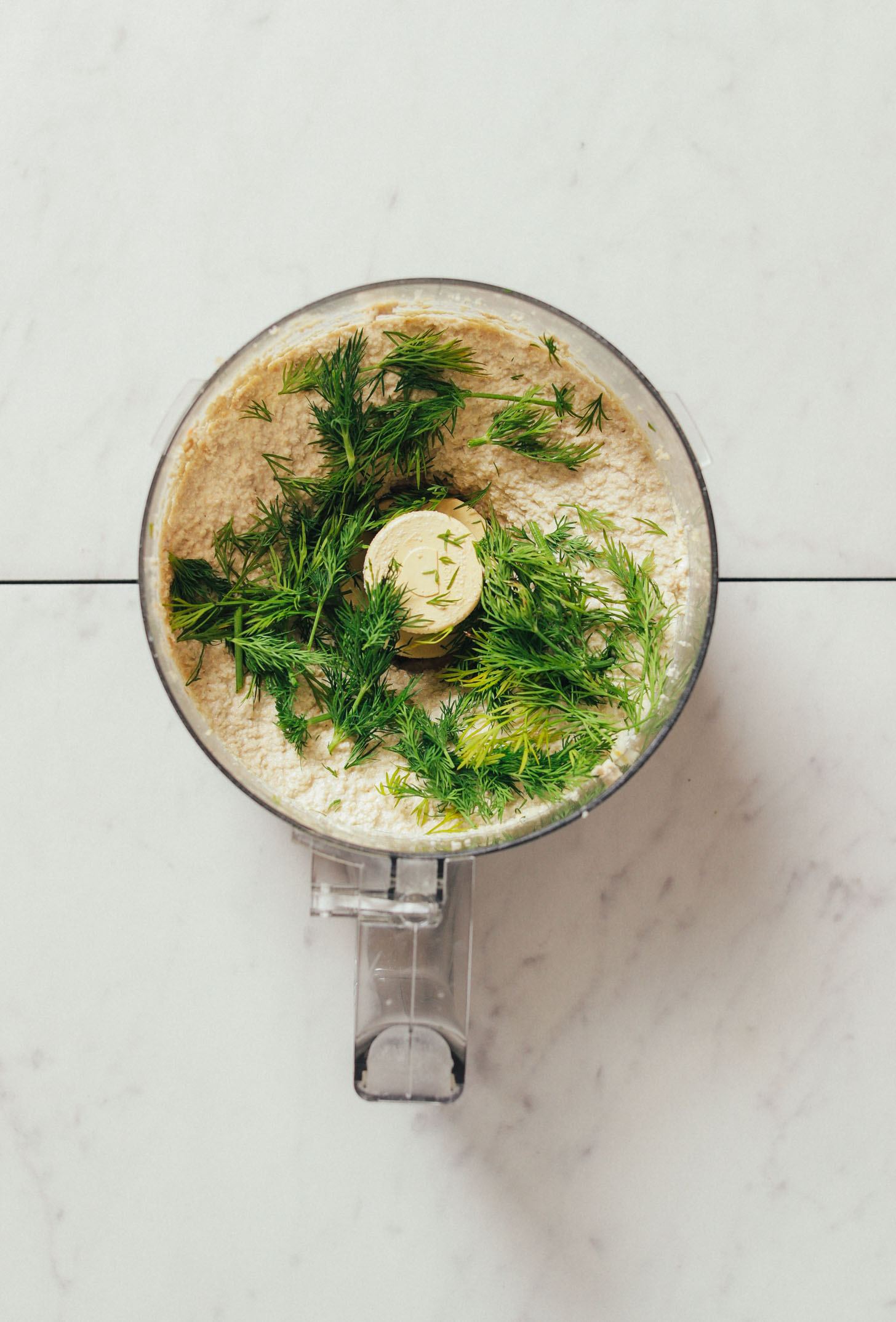 Food processor filled with Garlic Dill Sunflower Dip topped with fresh dill