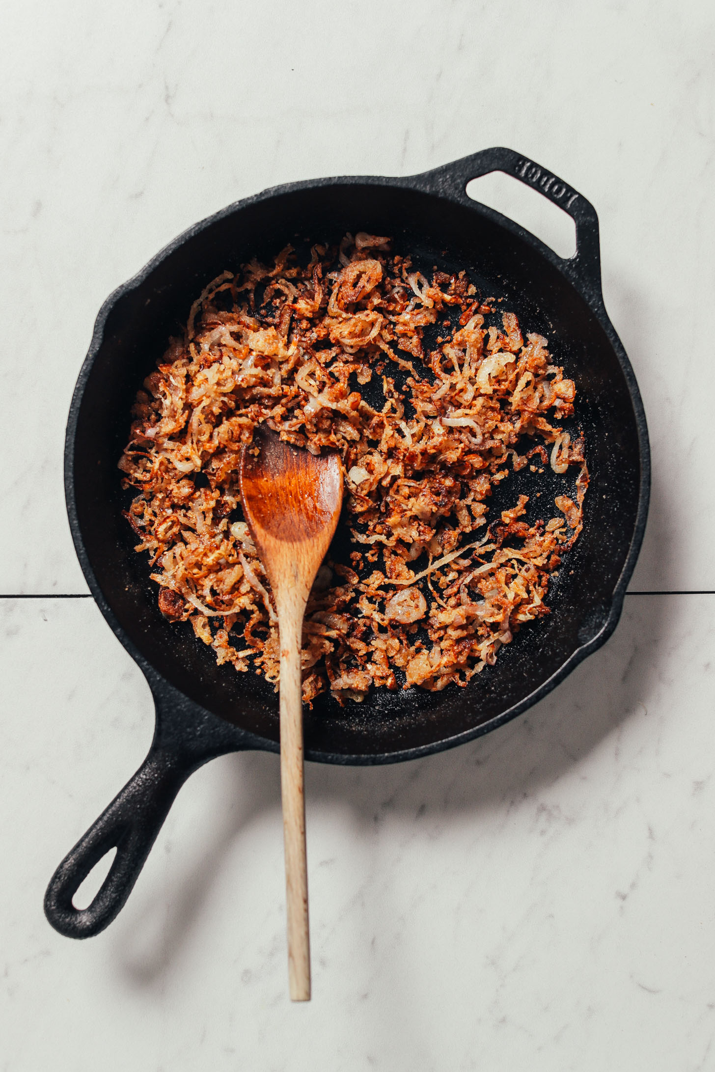 Cast-iron skillet with freshly cooked crispy shallots for making delicious vegan spring rolls
