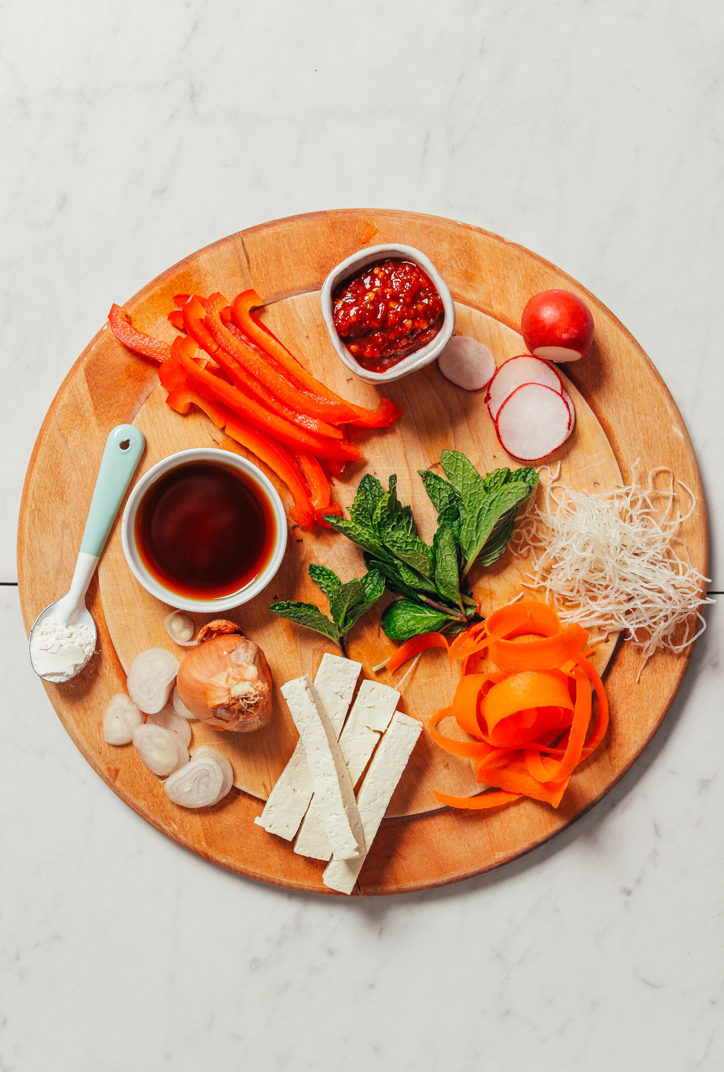 Wood cutting board with fresh vegetables and tofu for making Crispy Shallot Spring Rolls