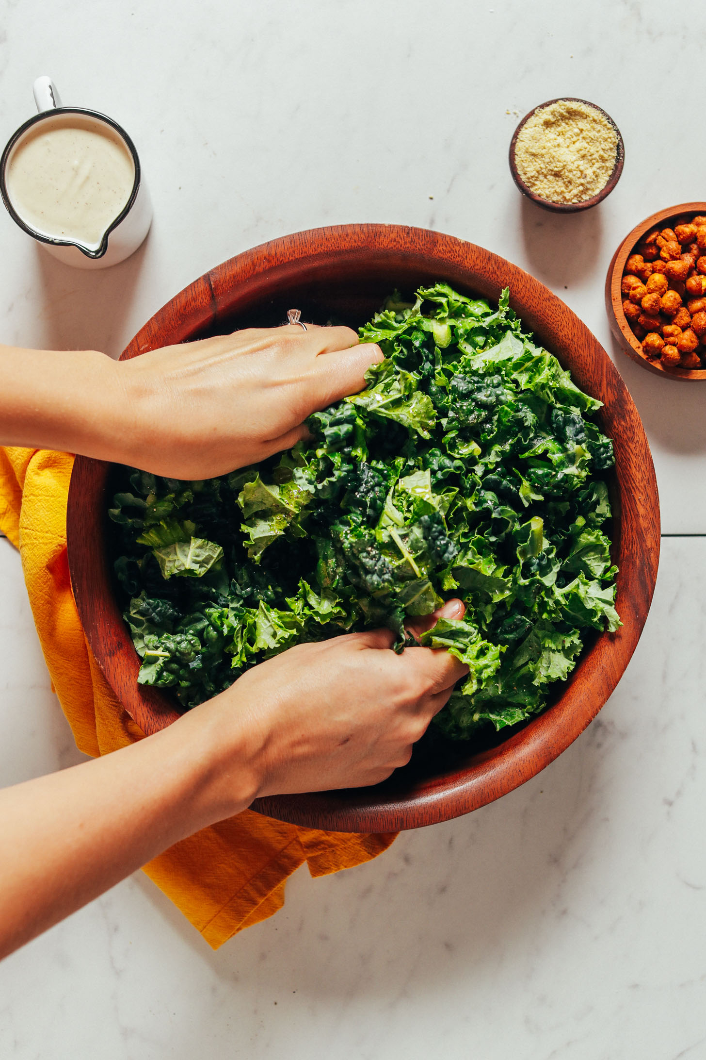 Using our hands to massage a bowl of kale for Chickpea Kale Caesar Salad