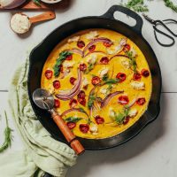 Pizza cutter resting on a skillet of our Vegan Frittata recipe