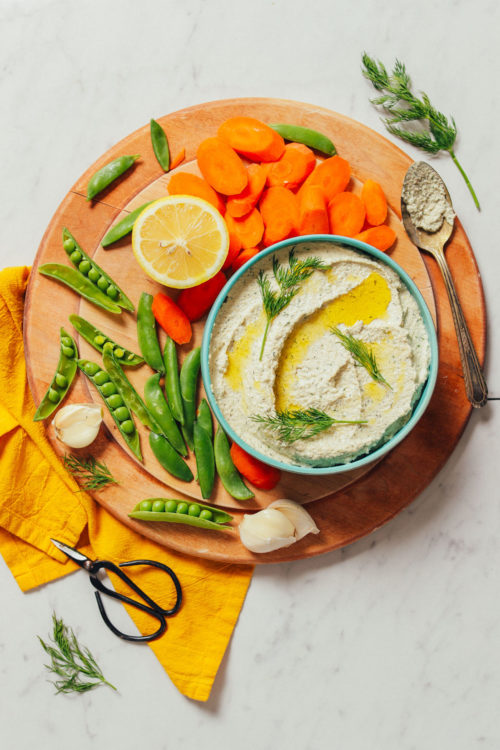 Bowl of Garlic Dill Sunflower Dip surrounded by fresh vegetables