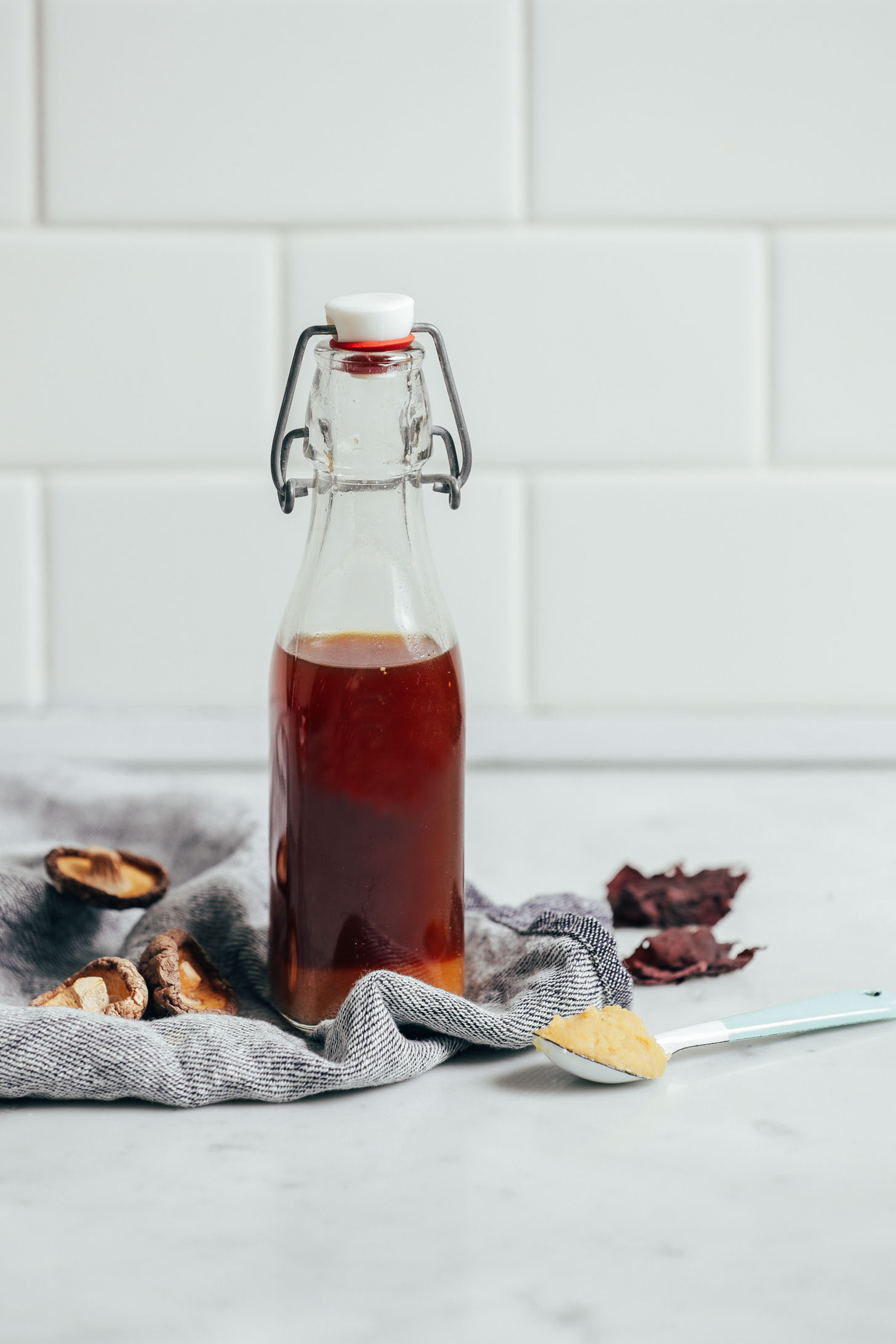 straight on shot of vegetarian fish sauce in a clear bottle with mushrooms on the side