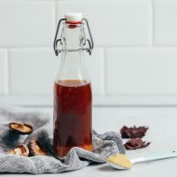 Bottle of homemade Vegan Fish Sauce on a blue linen with ingredients used to make it
