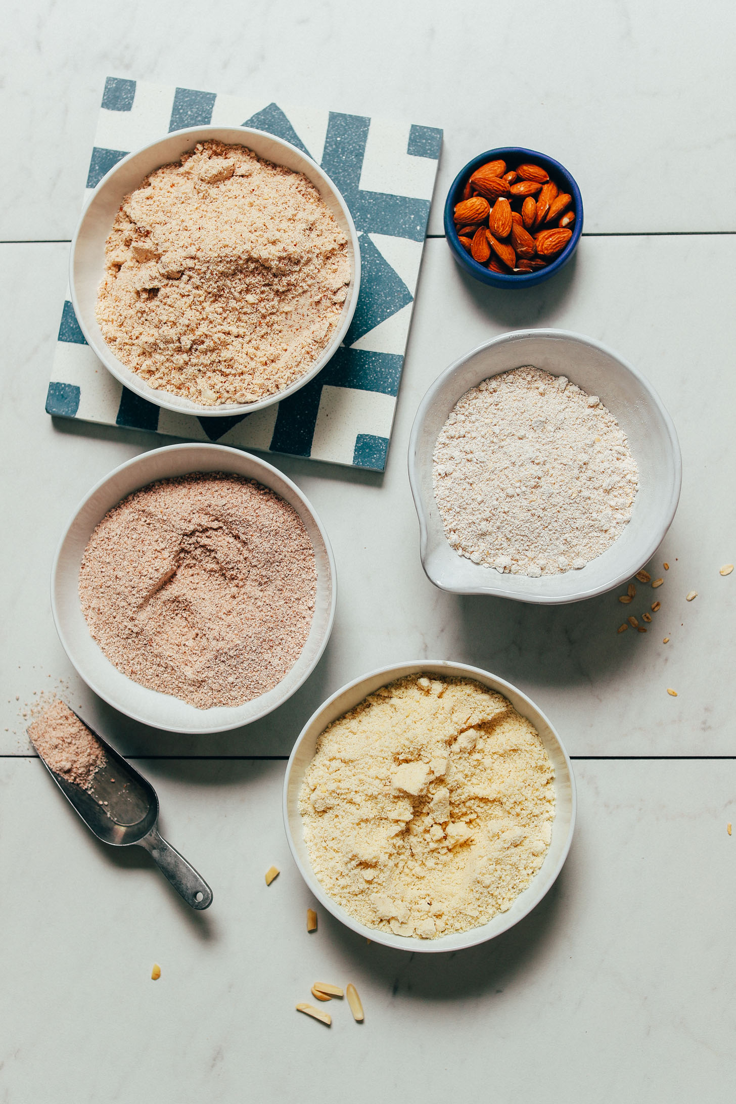 Bowls of oat flour, almond flour, almond meal, and almond pulp for our guide to how to use gluten-free flours
